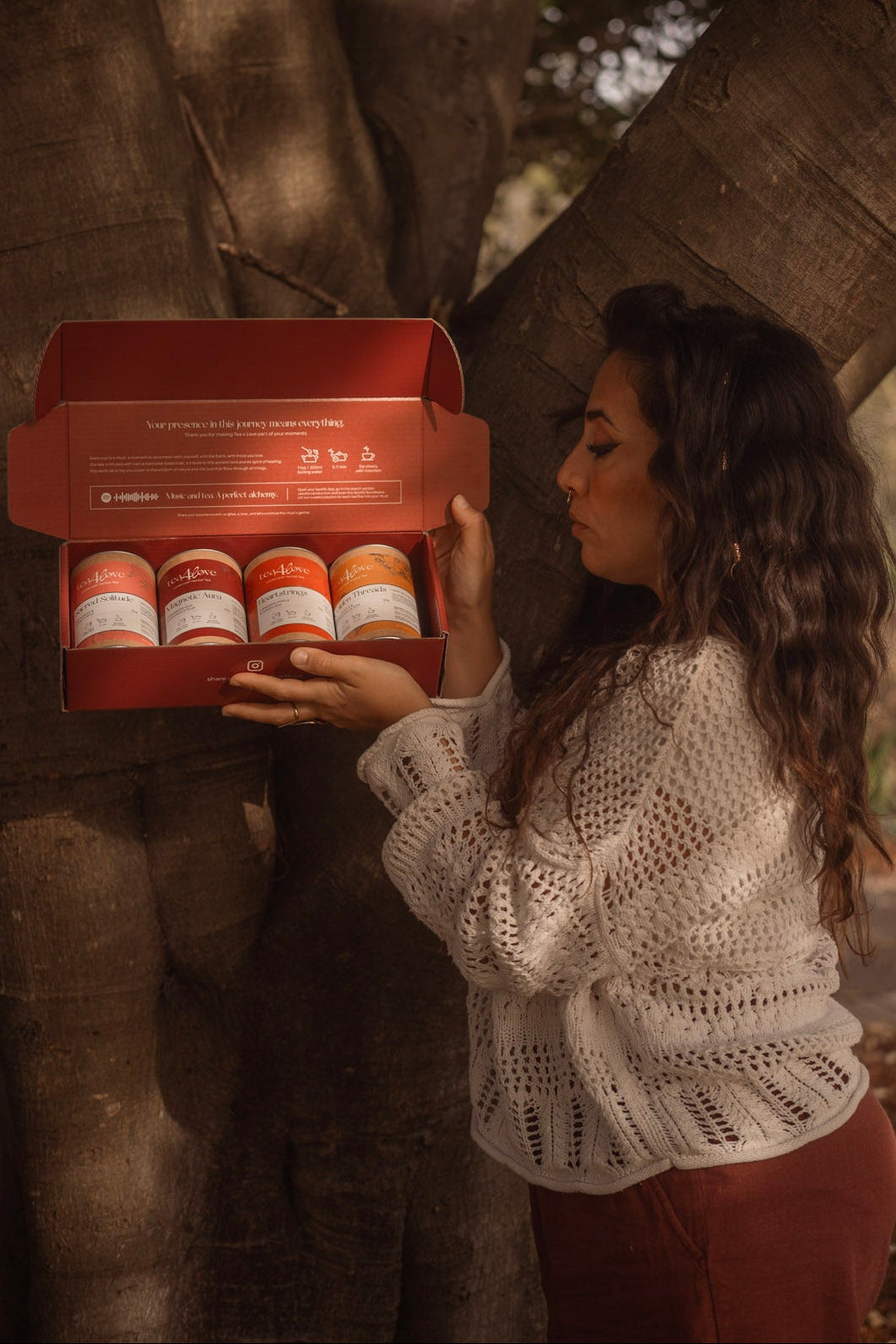 Woman holding a box of products under a tree